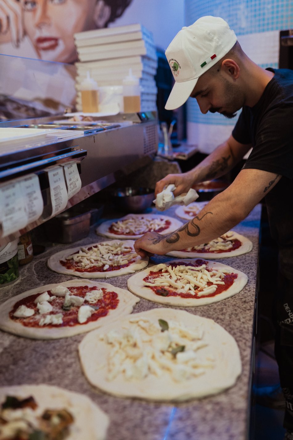 Il pizzaiolo farcisce le pizze