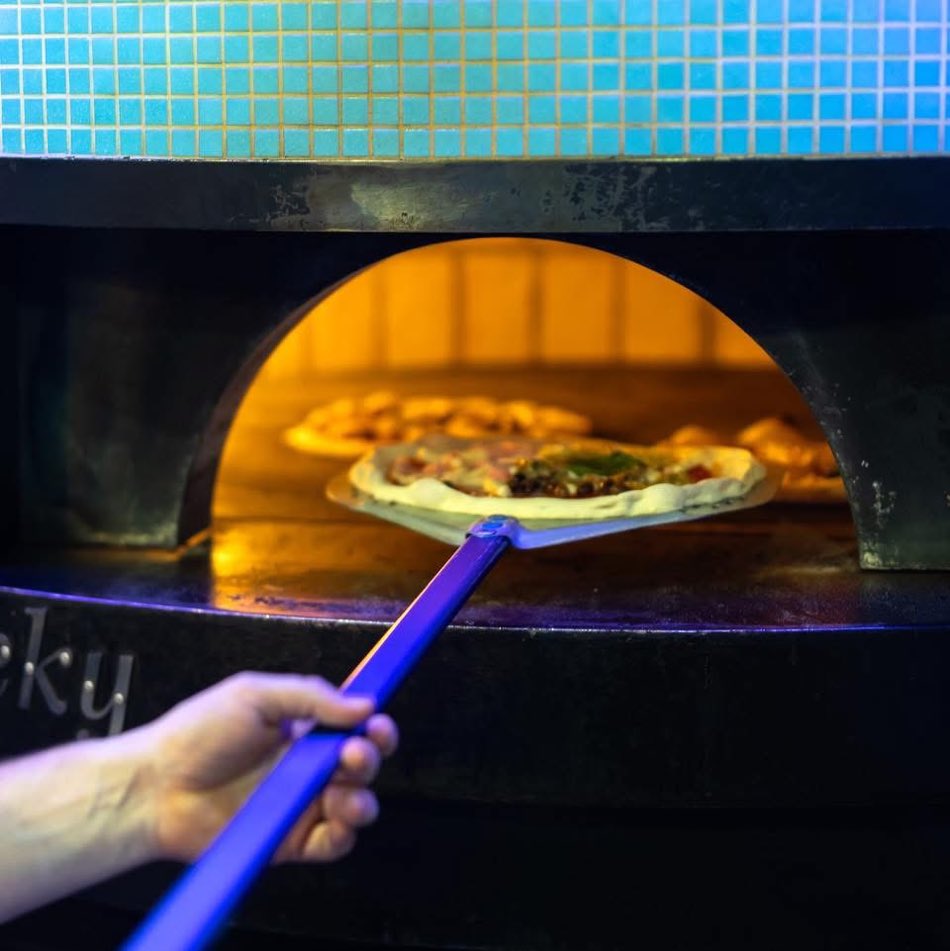 La pizza entra nel forno a legna e a gas